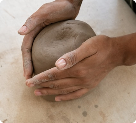 Mains en gros plan modelant un morceau d'argile lors d'un atelier d'initiation